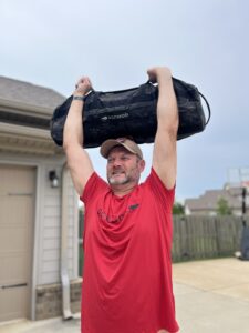 male in goruck toughmesh shirt lifting sandbag.
