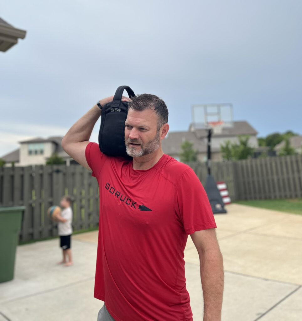 male sweating with goruck toughmesh tee and sand kettlebell