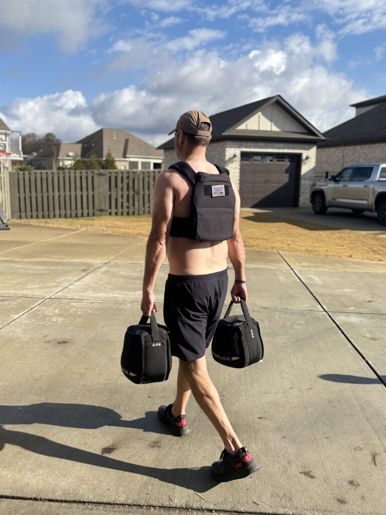 male with goruck rucking weight vest and sand kettlebells and rough runners